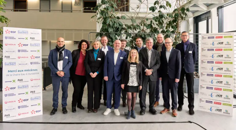 Treize personnes se tiennent à l'intérieur, devant des bannières publicitaires, et prennent la pose pour une photo de groupe lors d'un événement professionnel marquant l'inauguration de la Chaire Eau & Durabilité.