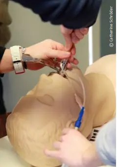 Au cours d'une séance de compétences cliniques, les participants s'entraînent à pratiquer l'intubation sur les voies respiratoires d'un mannequin d'entraînement médical à l'aide d'un laryngoscope et d'une sonde endotrachéale, mettant ainsi en pratique les gestes de soins essentiels dans le cadre d'une simulation médicale.