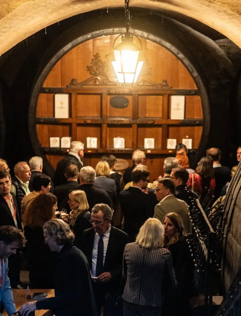 Un groupe de personnes, réunies dans une cave à vin faiblement éclairée, parsemée de fûts en bois et surmontée d'une grande lanterne suspendue, s'était rassemblé pour célébrer les succès du programme de reconnaissance de leur entreprise.
